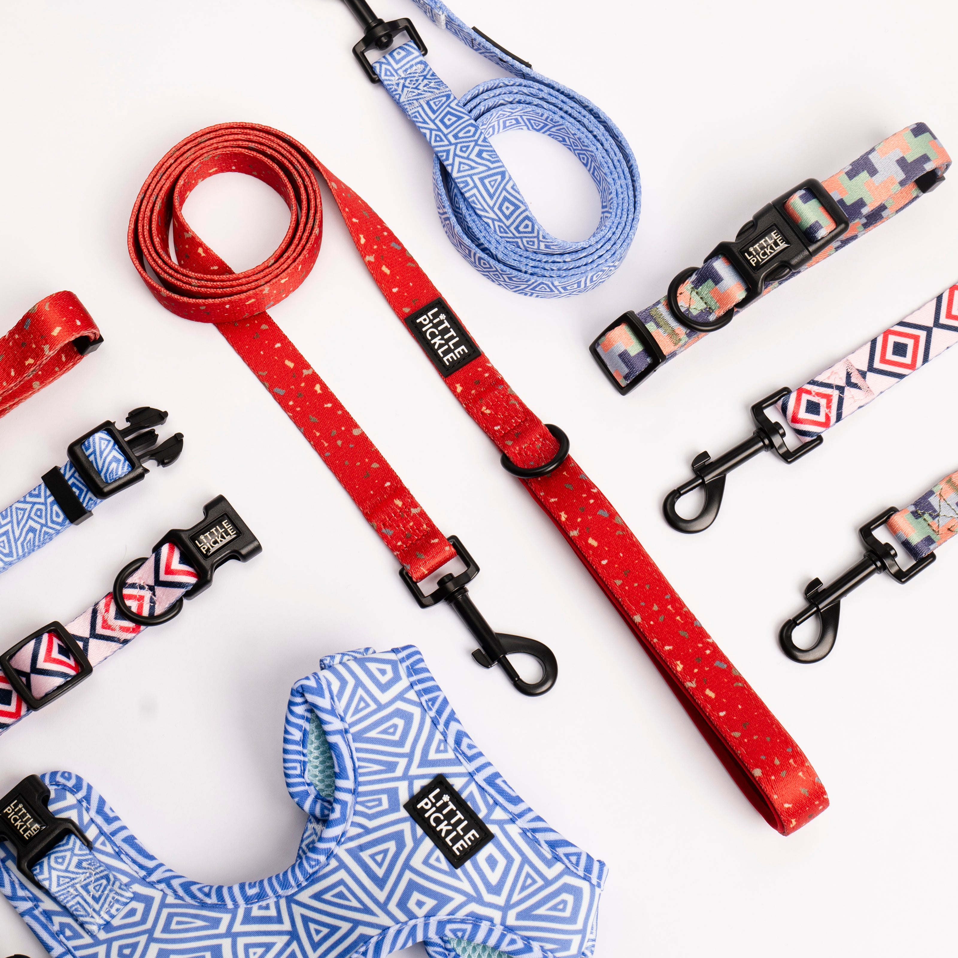 Assortment of colorful Little Pickle dog collars, leashes, and harnesses featuring various patterns and designs