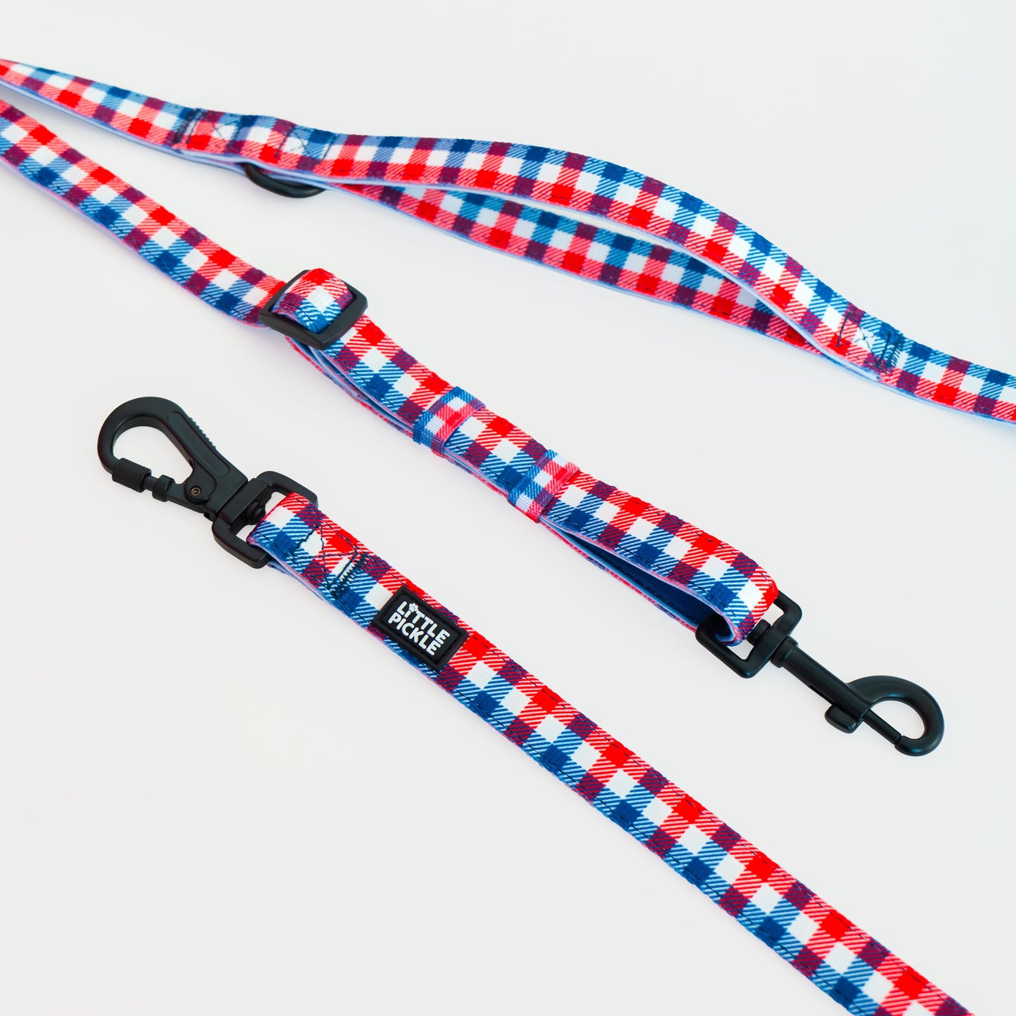 Two dog leashes with a red, white, and blue gingham pattern and black metal clasps, displayed on a clean white background.