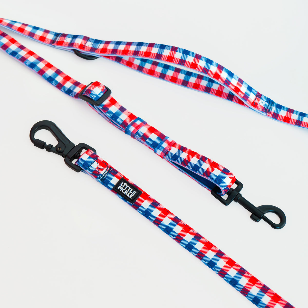 Two dog leashes with a red, white, and blue gingham pattern and black metal clasps, displayed on a clean white background.