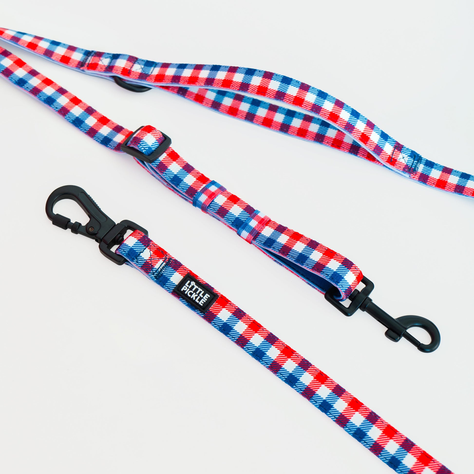 Two dog leashes with a red, white, and blue gingham pattern and black metal clasps, displayed on a clean white background.