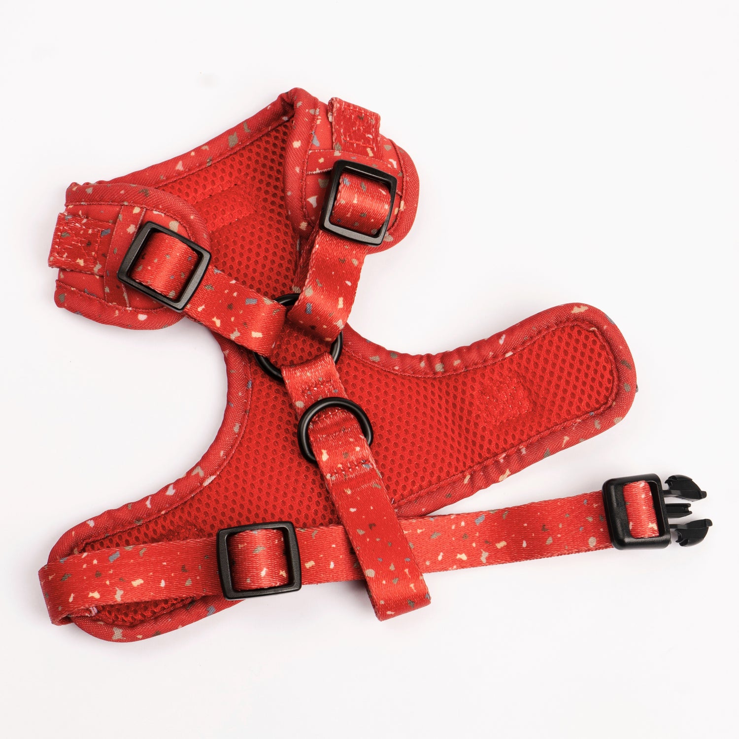 Red dog harness with gold speckled pattern, mesh panels, adjustable straps, and secure buckles on white background